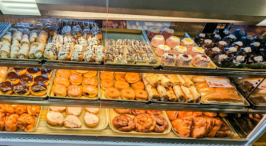A bakery display filled with rolls, pastries, doughnuts, and cakes