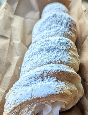 A powdered filled pastry served in a paper bag